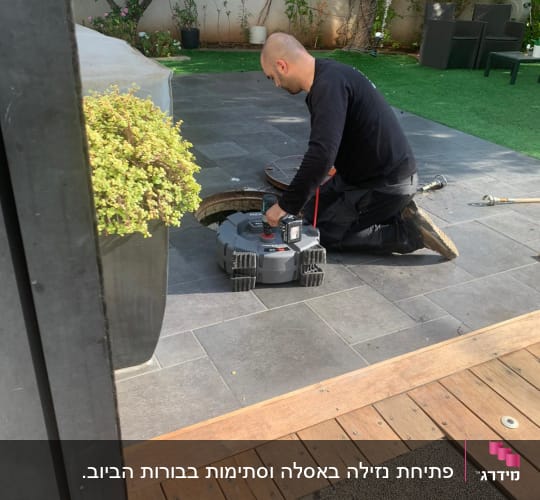 אדם עובד עם כלי עבודה על צינור בחצר